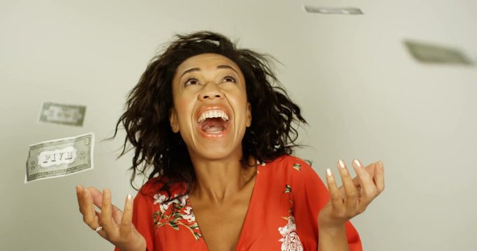 4K Dollar bills fall from the sky, excited surprised woman reaches out to catch them. Slow motion.