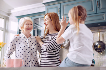 Bonding of generations. Cute little girl sitting on the kitchen counter, talking to her beloved...