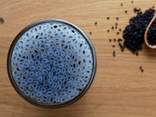 Swelled sweet basil or sabja seeds in shot glass with dried seeds in wooden spoon on wooden...