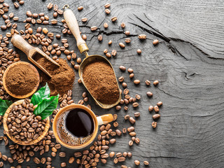 Roasted coffee beans, ground coffee and cup of coffee on wooden table.