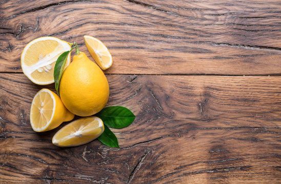Ripe lemons and lemon leaves on wooden background. Top view.