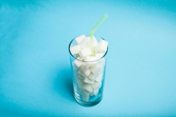 Too much sugar in drink on blue background, concept.