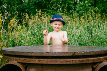 the boy in the hat plays in the green forest