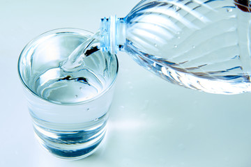 versando acqua con una bottigliadi plastica in un bicchiere con luce fredda