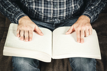 The blind man was reading a book written on Braille. Touch your finger on the braille code. A book with Braille text