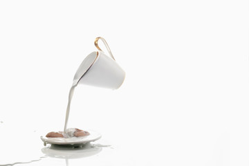 A white levitating cream-jug over a saucer with the biscuits