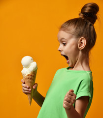 Pretty baby girl kid eating licking banana and vanilla ice cream in waffles cone
