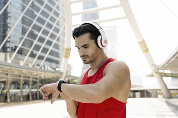 Athlete with earphones checking his smartwatch