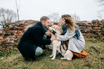 Fototapeta premium Pair of lovers walking with husky puppy outdoor in countryside in spring. Man and woman with their little beloved domestic pet hugging and resting at nature. Family together. Boy and girl in love.