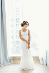 Wedding. Bride in beautiful dress  in white studio interior like at home. Trendy wedding style shot in full length. Young attractive caucasian brunette model like a bride