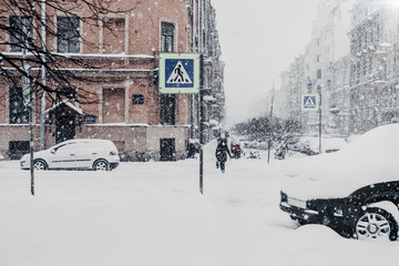 Outdoor shot of beautiful snowy city with transport and people, covered with thick white snow during blizzard. Winter, vehicle, transportation and people concept