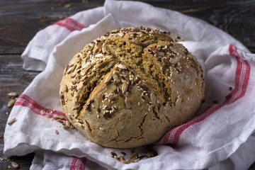 Simple rustic rye oat bread without yeast with seeds on a wooden table, selective focus