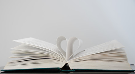 Open book with heart from the pages on a white background