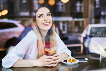 Portrait of smiling woman looking away having tea and dessert in cafe