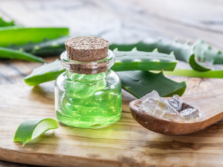 Fresh aloe leaves and aloe gel in the cosmetic jar on wooden table.