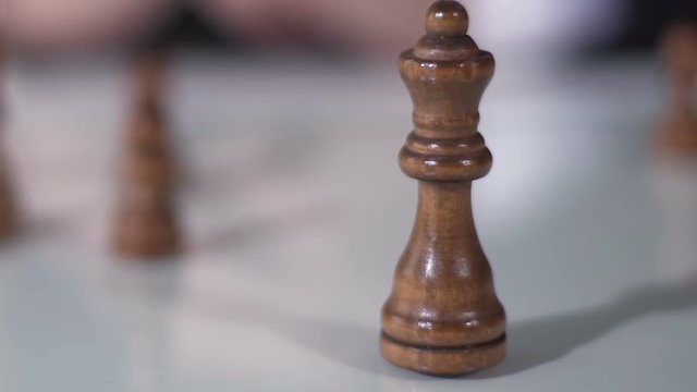 Male hand moving queen in chess game, fortune and corporation strategy, closeup