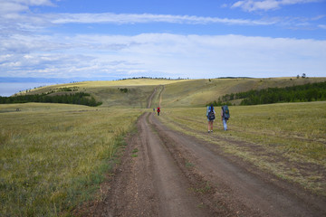 Fototapeta na wymiar tourists are on the broad road, amid vistas, Lake Baikal, Olkhon Island, Khuzhir town