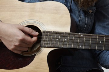 Fototapeta premium Young girl playing acoustic guitar with jeans shirt