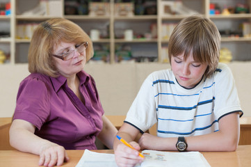 Teacher teaches a pupil at a table in the classroom