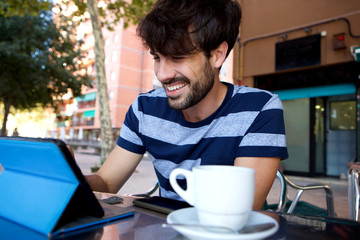 happy man using digital tablet at outdoor cafe