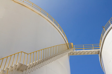 white fuel tanks against blue sky, white steel petroleum silo