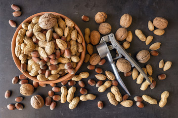  Assortment of nuts in their shell. Different kinds of nuts in  bowls and nutcracker . Healthy food.