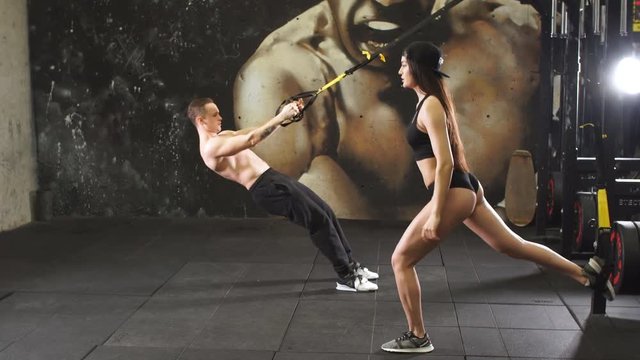 Muscular Athletes Doing Exercises with Fitness Trx System.