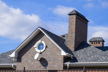 Asphalt shingle. Decorative bitumen shingles on the roof of a brick house.