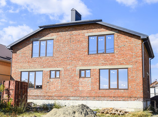 Two-storey house made of red brick. Metal-plastic windows. Newly built house.