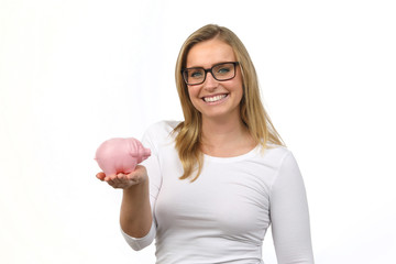Hübsche blonde Frau mit Brille hält ein Sparschwein auf ihrer Hand und lacht