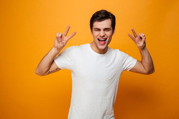 Joyful man in t-shirt showing peace gestures