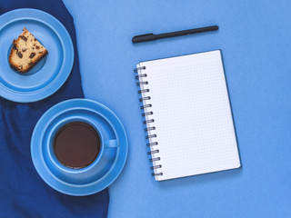 Top view goals list with notebook, cup of coffee on blue background. Flat lay, copy space