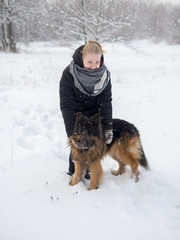 Young woman playing in winter with dog shepherd
