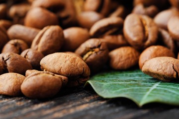 Roasted coffee beans with green leaf on the table 