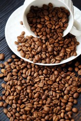 Roasted coffee beans in white mug on table 