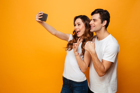 Pleased young lovely couple posing together while making selfie