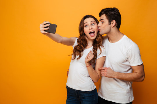 Young lovely couple posing together while making selfie on smartphone