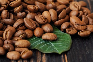 Roasted coffee beans with green leaf on the table 