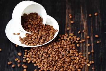 Roasted coffee beans in white mug on table  