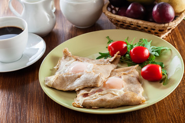 Crepes with ham, cheese and poached egg on a plate