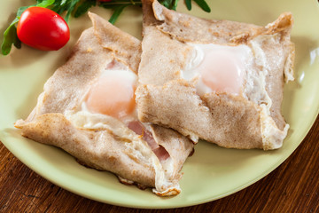 Crepes with ham, cheese and poached egg on a plate