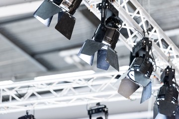 Lights attached to aluminium truss pointing down in a big exhibition hall - obrazy, fototapety, plakaty