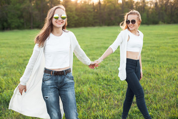 Two beautiful young females are walking on the field in the evening.