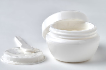 Open jar with face cream on a white background