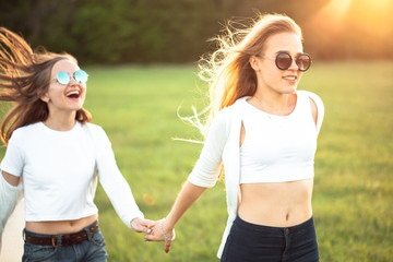 Charming girls are running on a field under the sunlight.