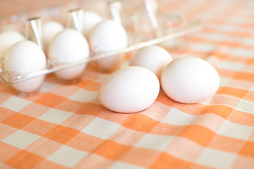Chicken eggs on a table with a checkered tablecloth.
