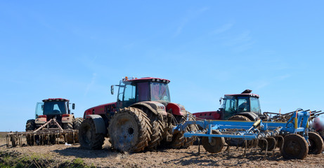 Fototapeta premium Red tractors plow the field. Rustic landscape. Agriculture. Farming