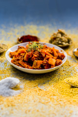 Traditional/regional carrot pickle,Daucus carota subsp. sativus pickle with ingredients like red pepper powder and turmeric powder with ginger garlic paste on a silver wooden floor.