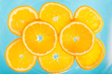 Sliced orange in blue soda water. Top view.
