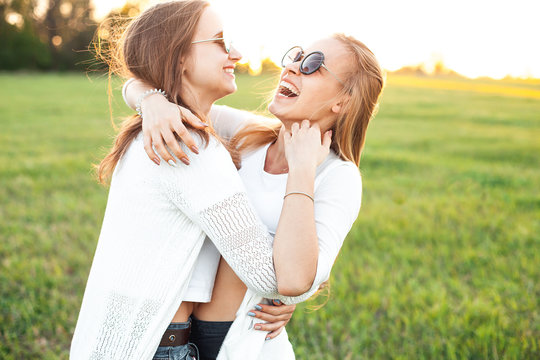 Two pretty females are waving on the green field under the sunlight in the evening.